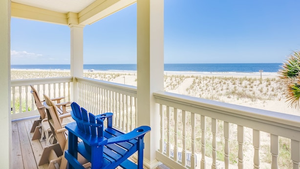 A covered porch with a view of the beach and ocean.