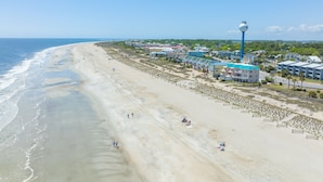 A beach with a water tower, buildings, and a road.
