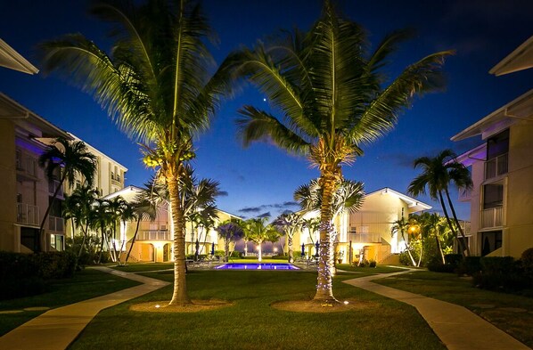 A resort with a pool, palm trees, and buildings with balconies.