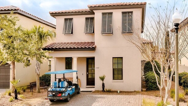 Une maison à deux étages avec une allée pavée, un véhicule de golf et un petit espace patio.