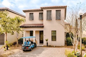 Une maison à deux étages, avec un toit en tuiles, un porche à l’avant et une allée.
