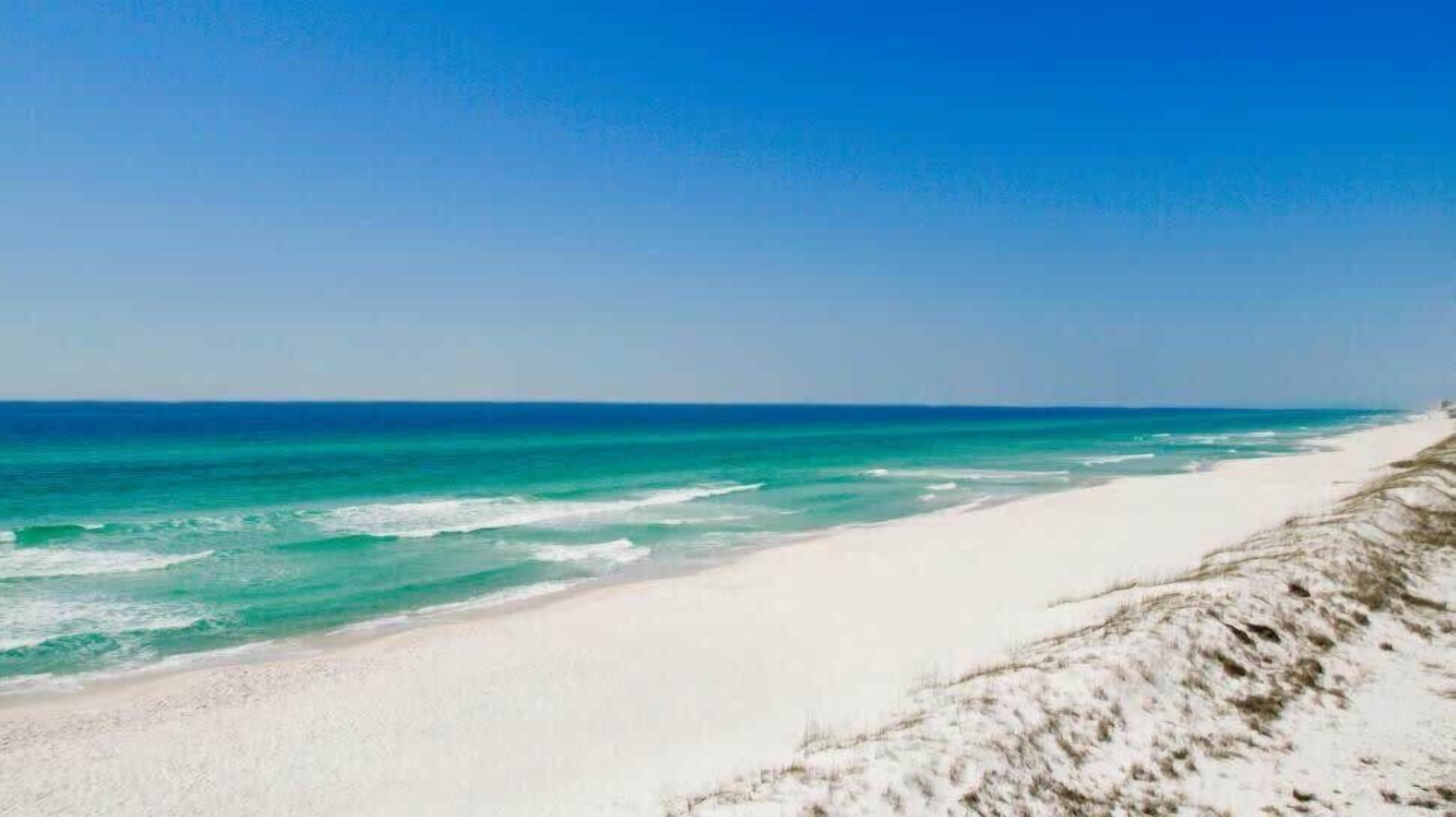 Une plage à l’eau turquoise et au sable blanc.
