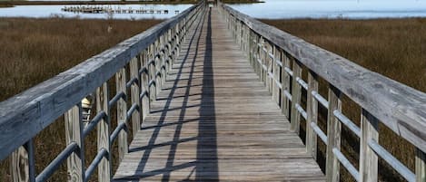 A wooden boardwalk leading to a distant shoreline with a clear sky.