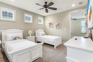 Un dormitorio con dos camas, un ventilador de techo y un espejo grande.
