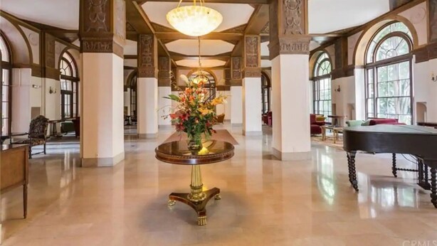 Eine geräumige Lobby mit einem prächtigen Kronleuchter, einem runden Tisch mit floraler Dekoration und einem Billardtisch.
