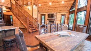 A wooden interior with a staircase, a dining table, and a fireplace. - Starry Respite: Hot Tub, 3 Fireplaces, Ping Pong, Foosball, Arcade, Pets allowed (Broken Bow)