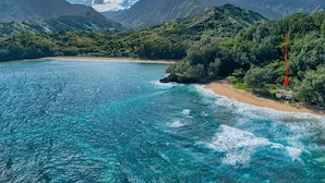 A coastal landscape with clear turquoise waters, a sandy beach, and lush green hills in the background. - Haena Beach House: Private Luxury Beachfront Home w/ Breathtaking Views (Hanalei)