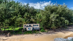 A beachfront property with a two-story house surrounded by dense tropical vegetation. - Haena Beach House: Private Luxury Beachfront Home w/ Breathtaking Views (Hanalei)