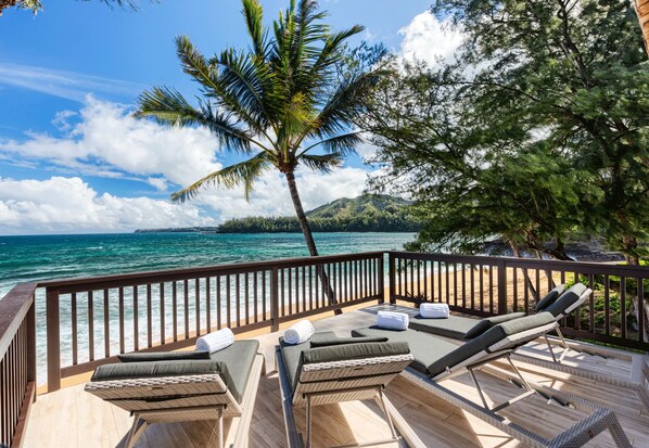 A deck with lounge chairs and a view of the ocean.