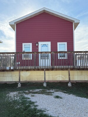 A two-story building with a red exterior, white trim, and a wooden fence in front. - Frenchy's Hideaways Cabin #5 (Custer)