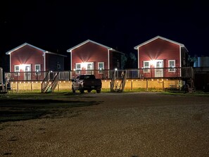 A row of red buildings with a gravel driveway and a parked truck. - Frenchy's Hideaways Cabin #5 (Custer)