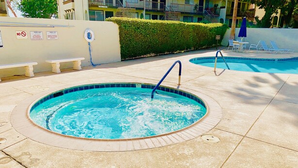 A swimming pool with a hot tub, lounge chairs, and a no swimming sign. - All Included 1BR Condo in Desert Hot Springs, CA - 15 minutes from Palm Springs. (Desert Hot Springs)