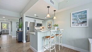 Une cuisine moderne avec des meubles blancs, des appareils en acier inoxydable et un îlot central doté de tabourets de bar.