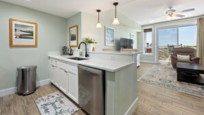 Une cuisine moderne avec des armoires blanches, des appareils en acier inoxydable et des luminaires suspendus.