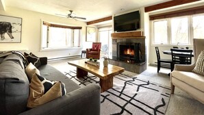 A cozy living room with a fireplace, comfortable seating, and large windows. - 1B, 1B MTN. Getaway Min. from Skiing.  (Wilson)