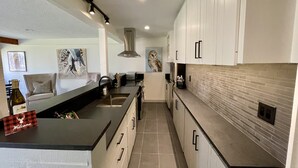 A modern kitchen with white cabinets, a black countertop, and a brick backsplash. - 1B, 1B MTN. Getaway Min. from Skiing.  (Wilson)