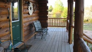 A log cabin with a porch, a green door, and two metal chairs. - Welcome to 'The Log Cab-Inn' - Where Great Memories Are Made (Atlantic Mine)