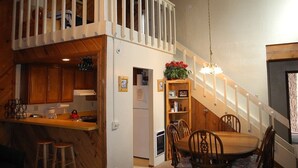 A compact kitchen with wooden cabinets, a dining area with a wooden table and chairs, and a small balcony with a railing. - Courchevel 8 (Mammoth Lakes)