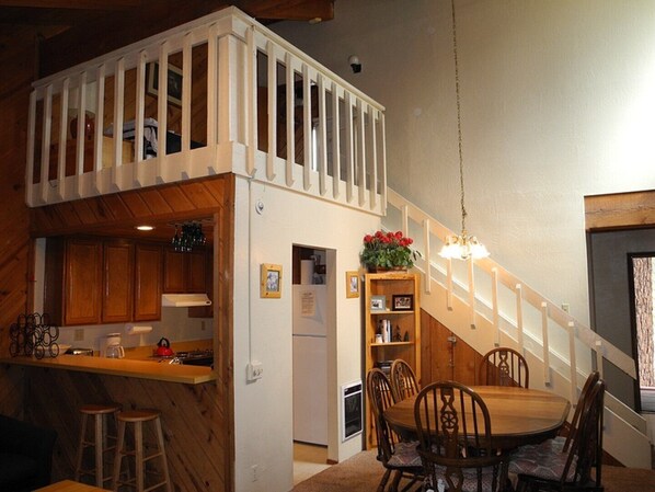 A compact kitchen with wooden cabinets, a dining area with a wooden table and chairs, and a small balcony with a railing. - Courchevel 8 (Mammoth Lakes)