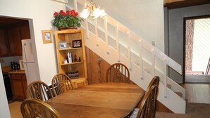 A dining area with a wooden table and chairs, a staircase, and a kitchen in the background. - Courchevel 8 (Mammoth Lakes)