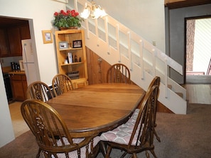 A dining area with a wooden table and chairs, a staircase, and a kitchen in the background. - Courchevel 8 (Mammoth Lakes)