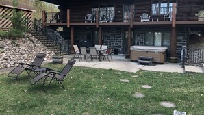 A two-story building with a patio area featuring outdoor furniture and a hot tub. - Custom Log Lake House on Wynne Lake  with Pontoon Boat. Summer 1 week Sat to Sat (Aurora)