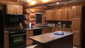 A kitchen with wooden cabinets, a granite countertop, a built-in oven, a microwave, and a coffee maker. - Custom Log Lake House on Wynne Lake  with Pontoon Boat. Summer 1 week Sat to Sat (Aurora)
