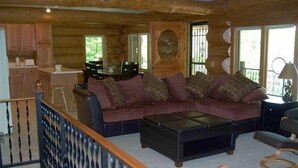 A log cabin interior with a living area featuring a sofa, coffee table, and dining table. - Custom Log Lake House on Wynne Lake  with Pontoon Boat. Summer 1 week Sat to Sat (Aurora)