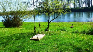 A grassy area with a wooden swing set and a small pond.