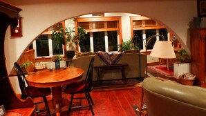 A cozy dining area with a wooden table, chairs, and a sofa under a wooden archway.