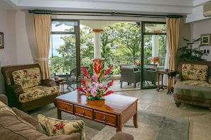 Een ruime woonkamer met een grote schuifpui naar een balkon, ingericht met een bank, een salontafel en een eethoek.