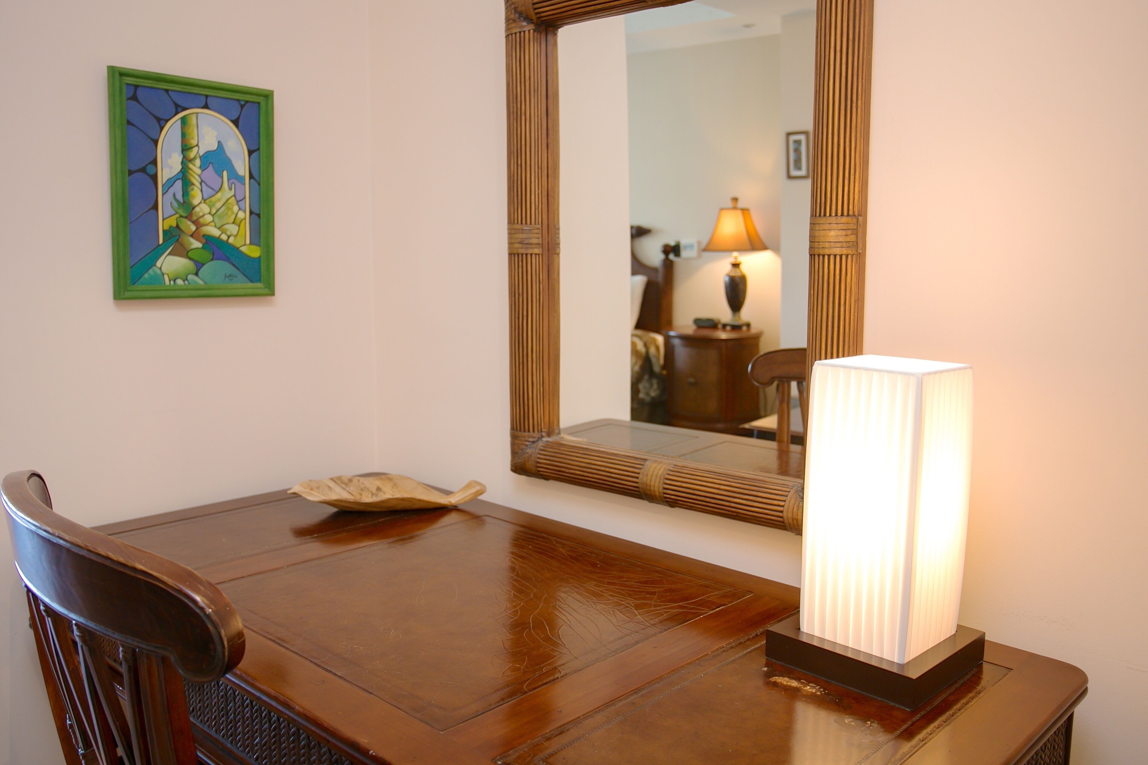 A dining table with chairs, a lamp, a framed artwork, and a mirror.