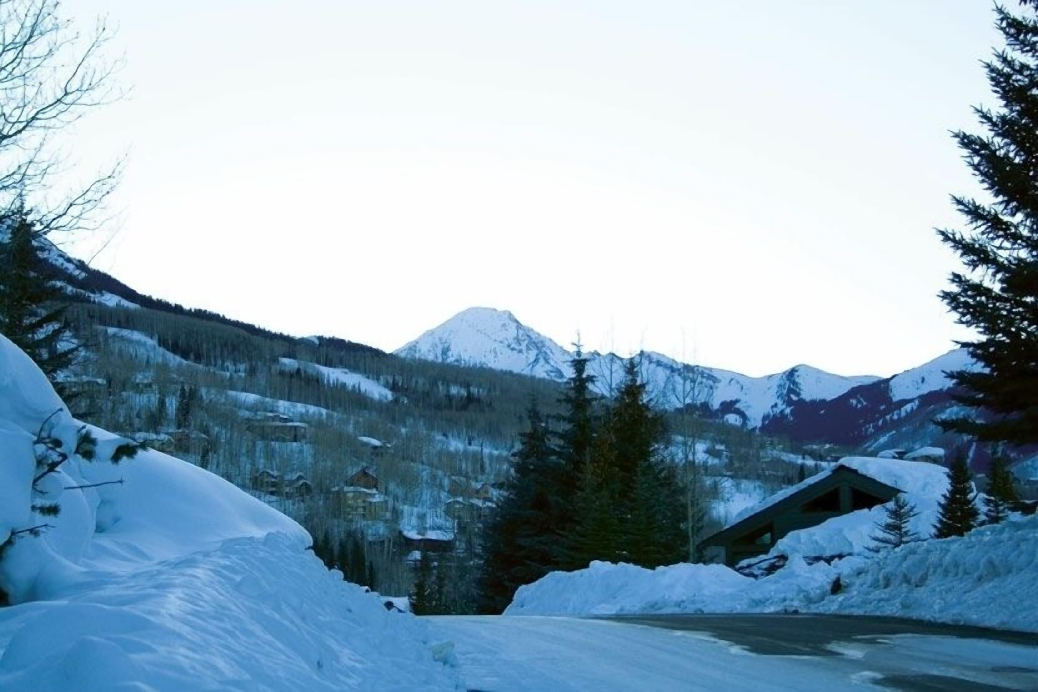 A snow-covered mountain landscape with a cabin and a road.