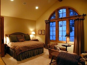 Relax in this inviting bedroom with a large bed, arched window, and cozy reading nook.
