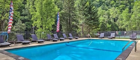 A swimming pool with lounge chairs and American flags.