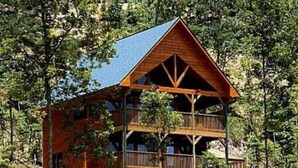Eine Hütte mit zweistöckiger Bauweise, Holzfassade und einem Balkon im oberen Bereich.
