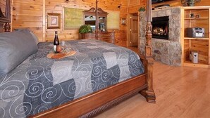 Ein Schlafzimmer in einer Blockhütte mit einem Bett, einem Kamin, einem Deckenventilator und einem Kamin aus Stein.