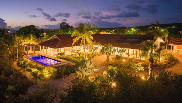 Un resort con piscina, zona de estar techada al aire libre y paneles solares.