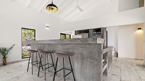 Una cocina moderna con una isla central, taburetes de bar y vistas al exterior.