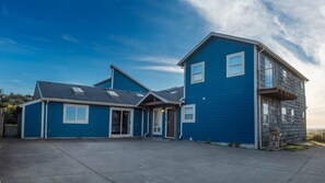 A two-story residential building with a blue exterior, a front porch, and a garage.