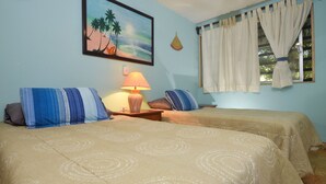 Una habitación con dos camas, una lámpara, un cuadro y una ventana con cortinas.