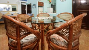 Un comedor con una mesa de vidrio rodeada de sillas de mimbre.