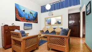 Una sala de estar con muebles de madera, un cuadro grande, un espejo y una cortina azul.
