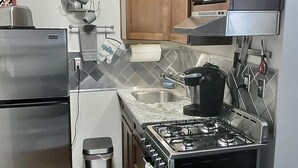 A compact kitchen with a stainless steel refrigerator, a gas stove, and a microwave. - Sophie’s Cottage with Private Garden - Walk to Old Town Roseville (Roseville)