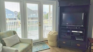 A living room with a sofa, a television, and a sliding glass door leading to a balcony. - Beautiful condo. Short walk to the beach!  Linens & Towels included. Beds Made! (Ocean Isle Beach)