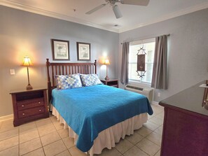 A bedroom with a bed, two bedside lamps, a ceiling fan, a window with curtains, and a wall-mounted air conditioner. - Beautiful condo. Short walk to the beach!  Linens & Towels included. Beds Made! (Ocean Isle Beach)