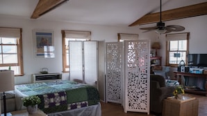 A bedroom with a bed, a desk, a chair, a TV, and a decorative partition. - Second story studio 1 1/2 blocks to beach (Santa Barbara)