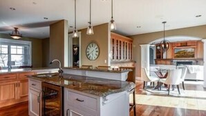Una cocina amplia con una isla central, iluminación colgante y muebles de madera.