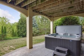 Puinen pergola, jonka alla on poreallas, ja ympärillä kaunis puutarha.