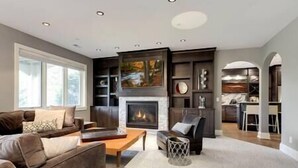 Una sala de estar moderna con chimenea, un sofá y una mesa de centro. Se ve una cocina al fondo.